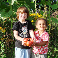 Happy kids holding veggies made larger by radiant solar heating.